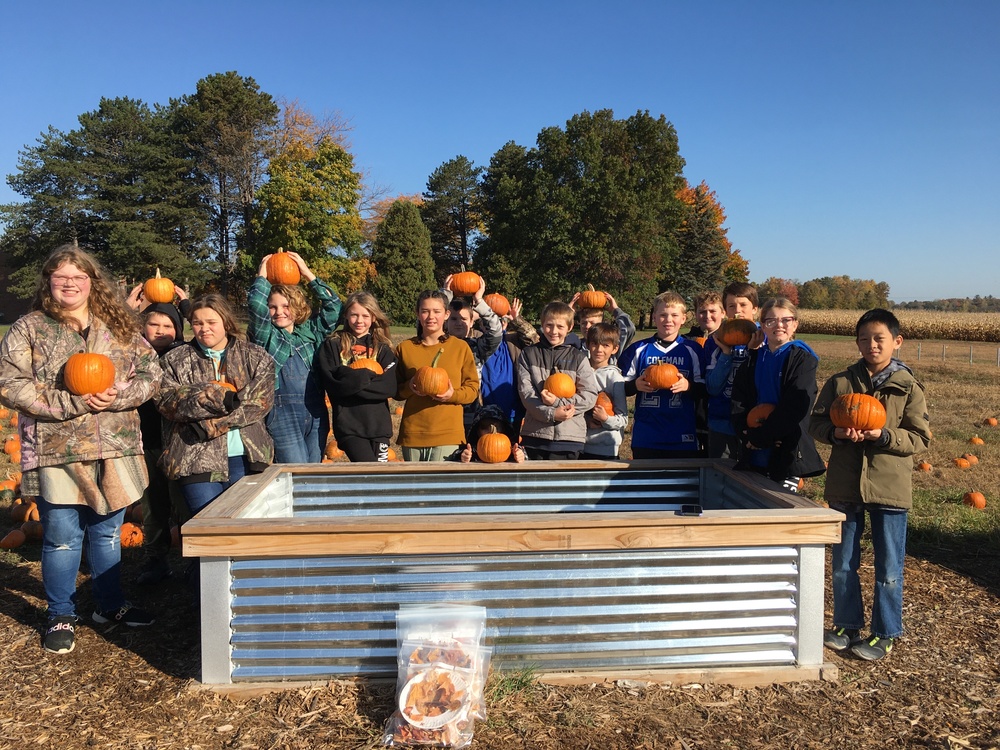 The 6th Grade Class posing with their pumpkins grown by the ag program